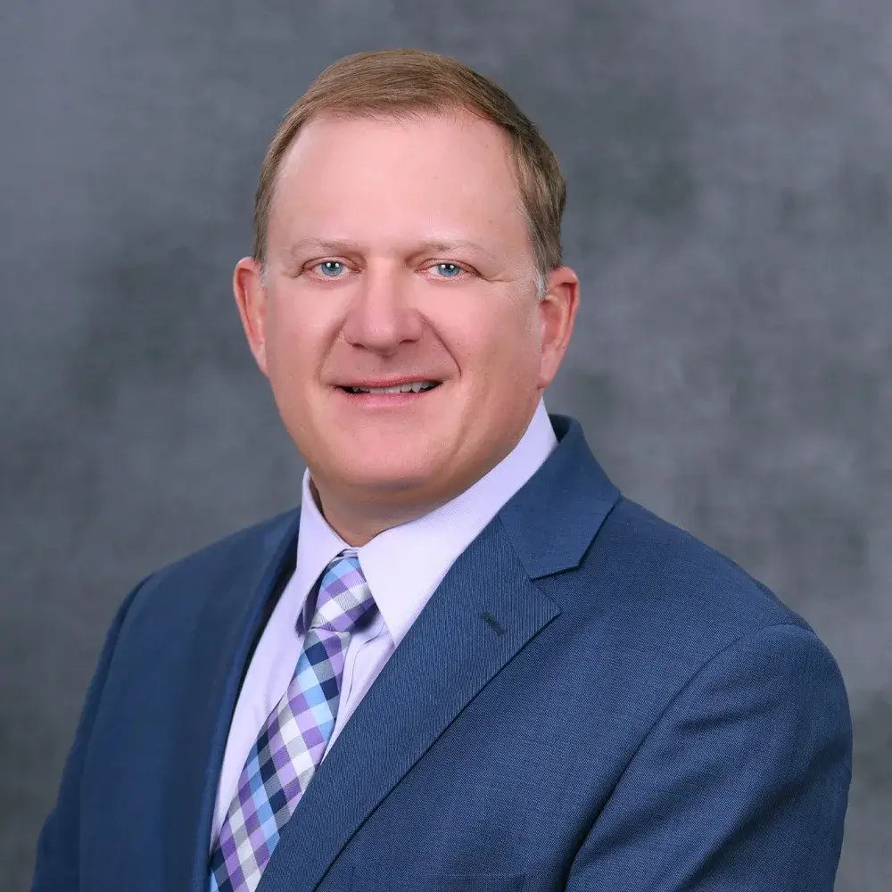 man smiling, wearing a suit and tie